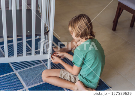 Father and older brother assembling a baby crib at home, preparing for a newborn arrival. Warm family moment full of care and anticipation. Parenthood, sibling bond and home preparation concept 137589629