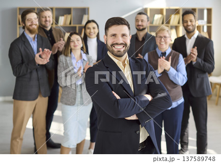 Confident young businessman with applauding team in office for career growth Confident young businessman with applauding team in office for career growth 137589748