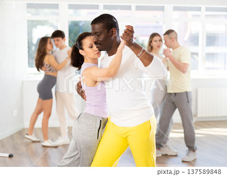 Woman with African man dancing waltz in couple during lesson at studio Woman with African man dancing waltz in couple during lesson at studio 137589848