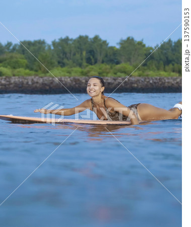Young Woman Maintains Steady Stance During Evening Paddleboarding Session 137590153