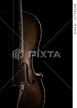 Elegant close-up of a wooden violin in shadow highlighting its beautiful contours and craftsmanship Elegant close-up of a wooden violin in shadow highlighting its beautiful contours and craftsmanship 137590306