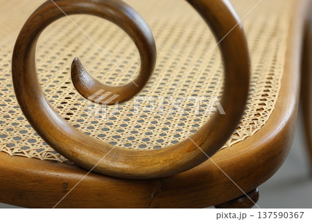 Curved wooden detail on a woven chair showcasing craftsmanship and design from a close perspective Curved wooden detail on a woven chair showcasing craftsmanship and design from a close perspective 137590367