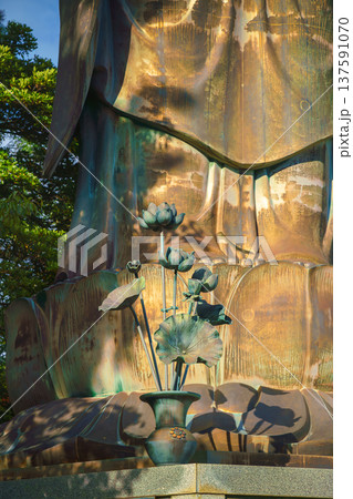 Sakata, Yamagata, japan - Oct 5 2024, A vertical close-up view of metal lotus flowers in a vase located at the feet of a giant statue of the Great Buddha at Jichi-in Temple, Sakata, Japan Sakata, Yamagata, japan - Oct 5 2024, A vertical close-up view of metal lotus flowers in a vase located at the feet of a giant statue of the Great Buddha at Jichi-in Temple, Sakata, Japan 137591070