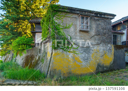 Sakata, Yamagata, japan - Oct 5 2024, panoramic view of the stone wall of an old house covered with foliage, ivy and lichen, on the river embankment, at daytime, without people, Sakata, Japan Sakata, Yamagata, japan - Oct 5 2024, panoramic view of the stone wall of an old house covered with foliage, ivy and lichen, on the river embankment, at daytime, without people, Sakata, Japan 137591108