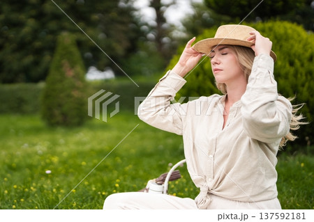 Enjoying a peaceful moment in a sunlit garden wearing a straw hat 137592181