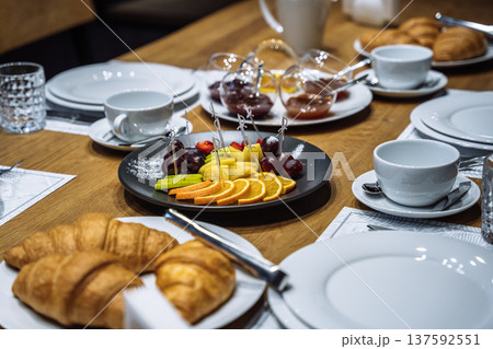 Selective focus on a fruit platter and golden croissants served for breakfast on a wooden table 137592551