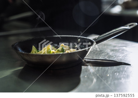 Sizzling broccoli and cauliflower frying in a pan with steam in a professional restaurant kitchen Sizzling broccoli and cauliflower frying in a pan with steam in a professional restaurant kitchen 137592555
