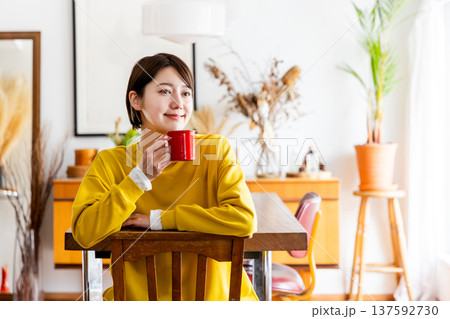 椅子に反対向きに跨いで座りコーヒーを飲む女性 椅子に反対向きに跨いで座りコーヒーを飲む女性 137592730