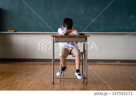 教室の机でうつ伏せに寝ている小学生の男の子 137593271