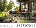 Beautiful outdoor terrace with modern chairs, table, and BBQ in a sunny garden setting. 137597214