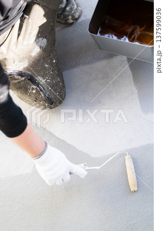 ベランダの防水塗装メンテナンス：長柄ローラーで防水材を塗布する作業員　手元 137599036