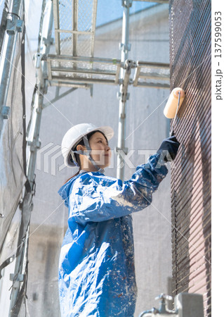 住宅リフォームの最前線：明るい笑顔で壁を塗る女性塗装工 137599053