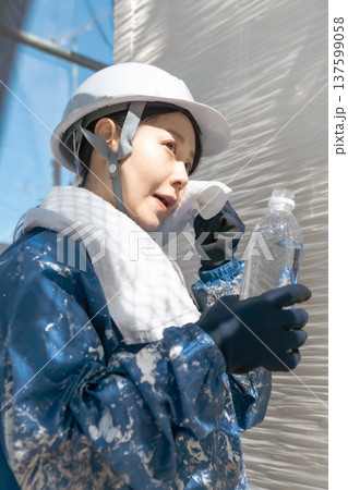 建設業界の安全衛生管理：作業の合間にリフレッシュするヘルメット姿の女性 137599058