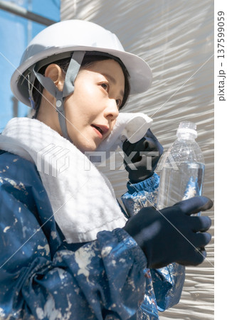 建設業界の安全衛生管理：作業の合間にリフレッシュするヘルメット姿の女性 137599059