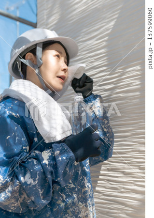 建設業界の安全衛生管理:作業の合間にリフレッシュするヘルメット姿の女性 建設業界の安全衛生管理:作業の合間にリフレッシュするヘルメット姿の女性 137599060