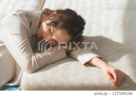 日の当たるソファでうたた寝する女性 137599106