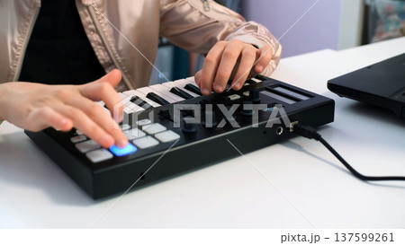 Girl creating music on a midi keyboard, enjoys her creative time at home, hobby concept 137599261