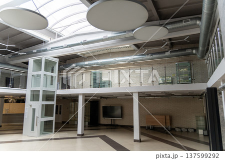 Modern interior of an industrial-style office hall with glass elevator Modern interior of an industrial-style office hall with glass elevator 137599292