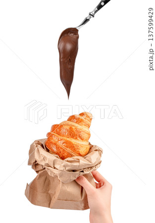 Chocolate spread dripping from spoon onto croissant in paper bag isolated on white Chocolate spread dripping from spoon onto croissant in paper bag isolated on white 137599429