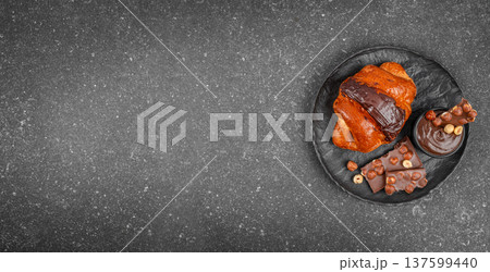 Chocolate croissant with chocolate spread and hazelnut chocolate on dark plate with copy space 137599440