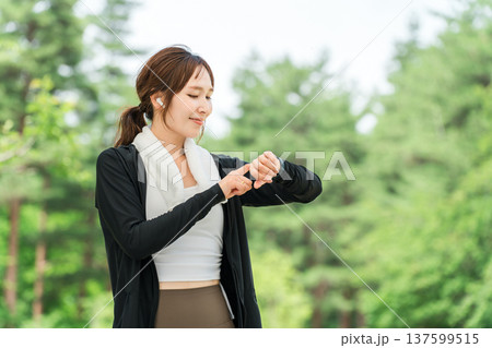 運動中にスマートウォッチを操作する女性(ヘルスケア・音楽・ワークアウト) 運動中にスマートウォッチを操作する女性(ヘルスケア・音楽・ワークアウト) 137599515