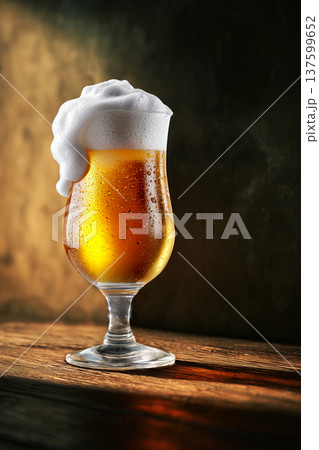 Foamy amber beer in a pint glass, on a rustic wooden bar background, conveying a concept of refreshment 137599652