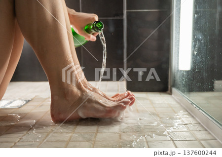 Foot fetish. A woman pours beer from a bottle onto her toes. Foot fetish. A woman pours beer from a bottle onto her toes. 137600244