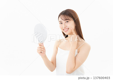 白背景でスキンケアをする女性のビューティーイメージ 137600403