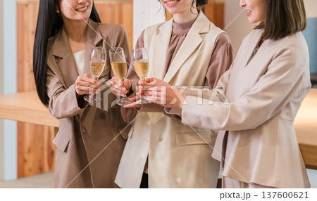 シャンパンを持ってオフィスに並ぶビジネスウーマン（チームワーク,決起集会,祝勝会,お祝い） 137600621