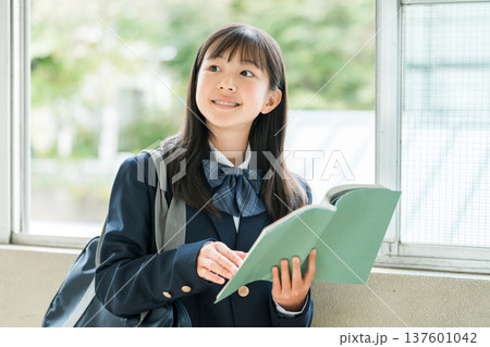 学校の廊下で本を持つ小学生,中学生,高校生の女子生徒 学校の廊下で本を持つ小学生,中学生,高校生の女子生徒 137601042