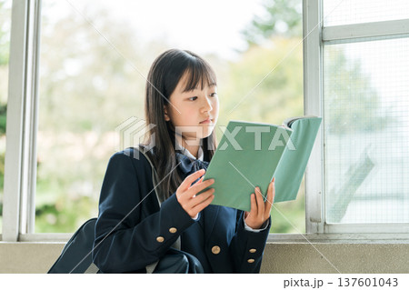 学校の廊下で本を持つ小学生,中学生,高校生の女子生徒 137601043