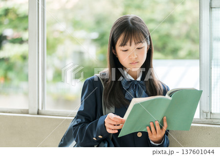 学校の廊下で本を持つ小学生,中学生,高校生の女子生徒 137601044