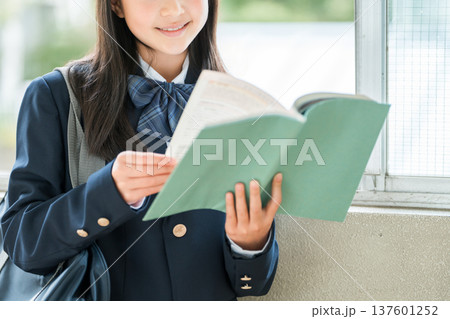 学校の廊下で本を持つ小学生,中学生,高校生の女子生徒 137601252