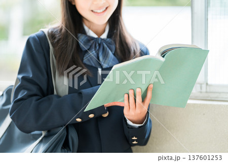 学校の廊下で本を持つ小学生,中学生,高校生の女子生徒 137601253