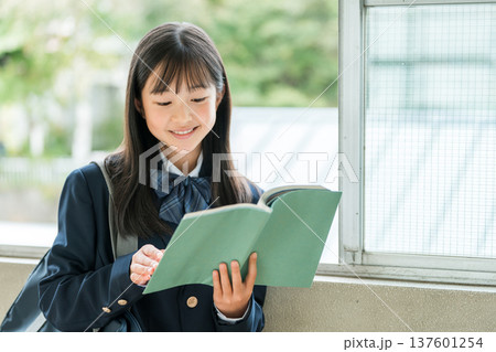 学校の廊下で本を持つ小学生,中学生,高校生の女子生徒 137601254