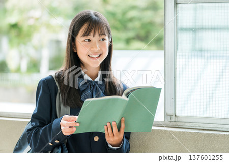 学校の廊下で本を持つ小学生,中学生,高校生の女子生徒 137601255