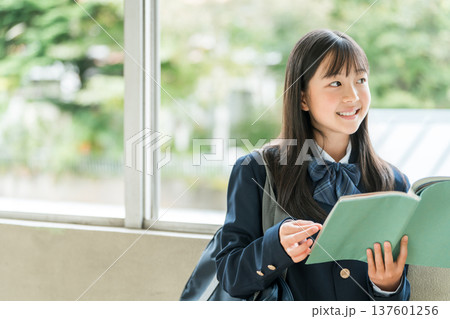 学校の廊下で本を持つ小学生,中学生,高校生の女子生徒 137601256