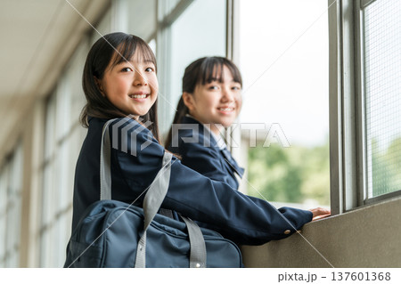 学校の廊下で会話する制服姿の中学生の女子生徒 137601368