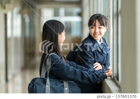 学校の廊下で会話する制服姿の中学生の女子生徒 137601370