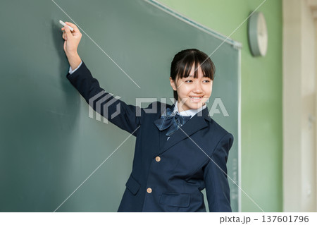 教室の黒板にチョークで文字を書く中学生の女子生徒 教室の黒板にチョークで文字を書く中学生の女子生徒 137601796
