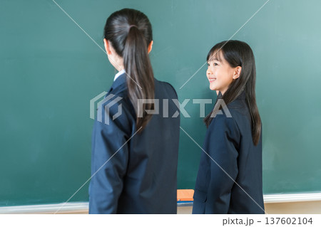 教室の黒板にチョークで文字を書く中学生の女子生徒 教室の黒板にチョークで文字を書く中学生の女子生徒 137602104