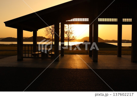 休憩棟を影絵のように染めて消えいく湖山池の夕陽 137602217