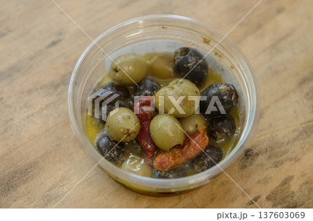 プラスチック容器に入った黒と緑のオリーブとドライトマトの惣菜 137603069