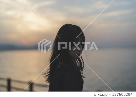 夕暮れの海を眺める女性 137603294
