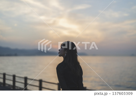 夕暮れの海を眺める女性 137603309