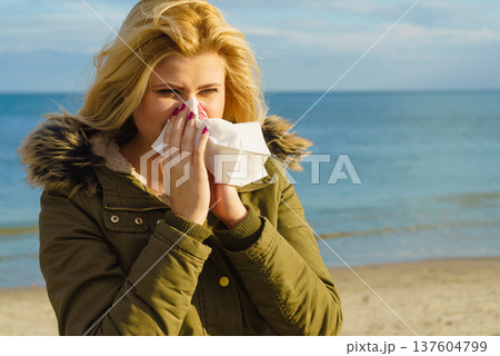 Sneezing woman into handkerchief, outside sunny shot Sneezing woman into handkerchief, outside sunny shot 137604799