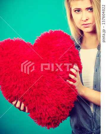 Sad woman holding red pillow in heart shape 137604822