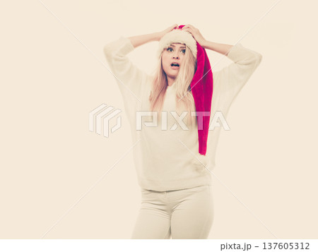 Shocked woman wearing Santa Claus helper hat 137605312