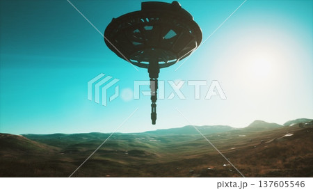 A sleek, high tech device hovers above a vast, green valley, illuminated by sunlight. The landscape features rolling hills and distant mountains, creating a serene environment. A sleek, high tech device hovers above a vast, green valley, illuminated by sunlight. The landscape features rolling hills and distant mountains, creating a serene environment. 137605546