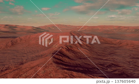 A vast desert scene unfolds with rolling red and brown hills under a serene blue sky. Soft clouds drift lazily, adding to the picturesque atmosphere of this arid environment. 137605640